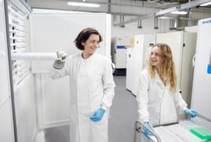 Two people in white lab coats inspecting samples taken from a freezer in the Biorepository