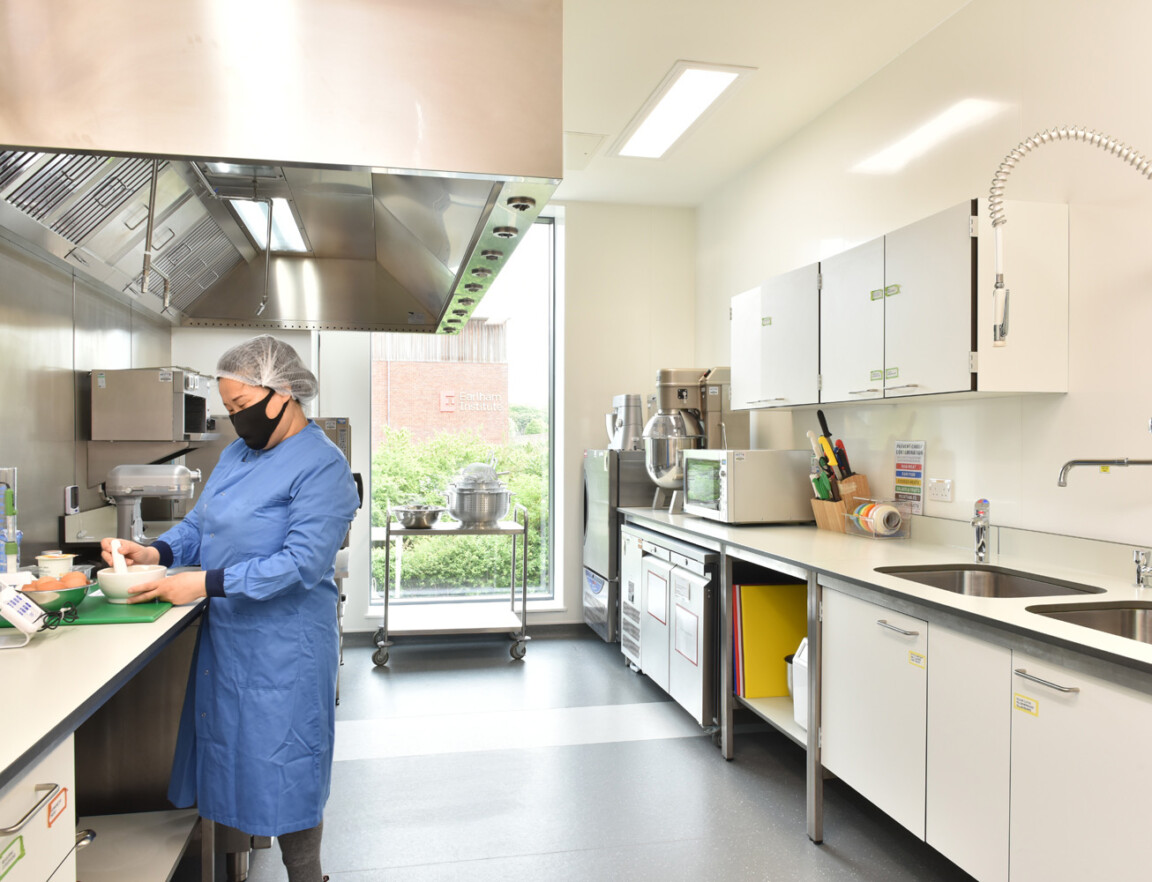 A person in a blue lab coat working on an experiment in the Clinical Research Facility
