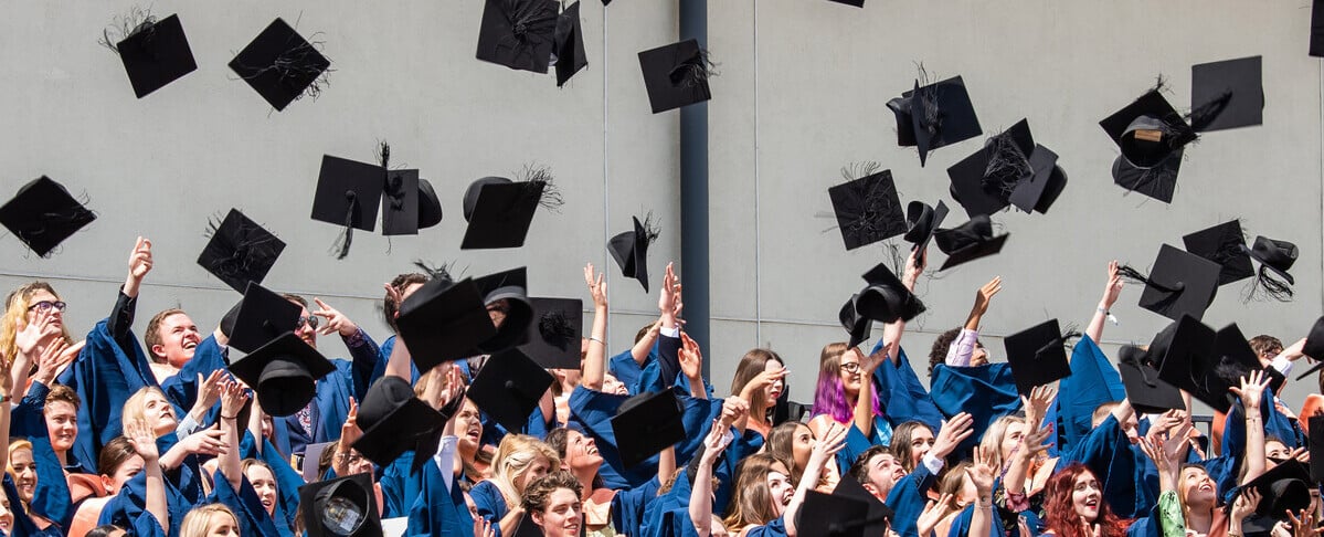 A group of students in graduation robes throwing their mortarboards into the air