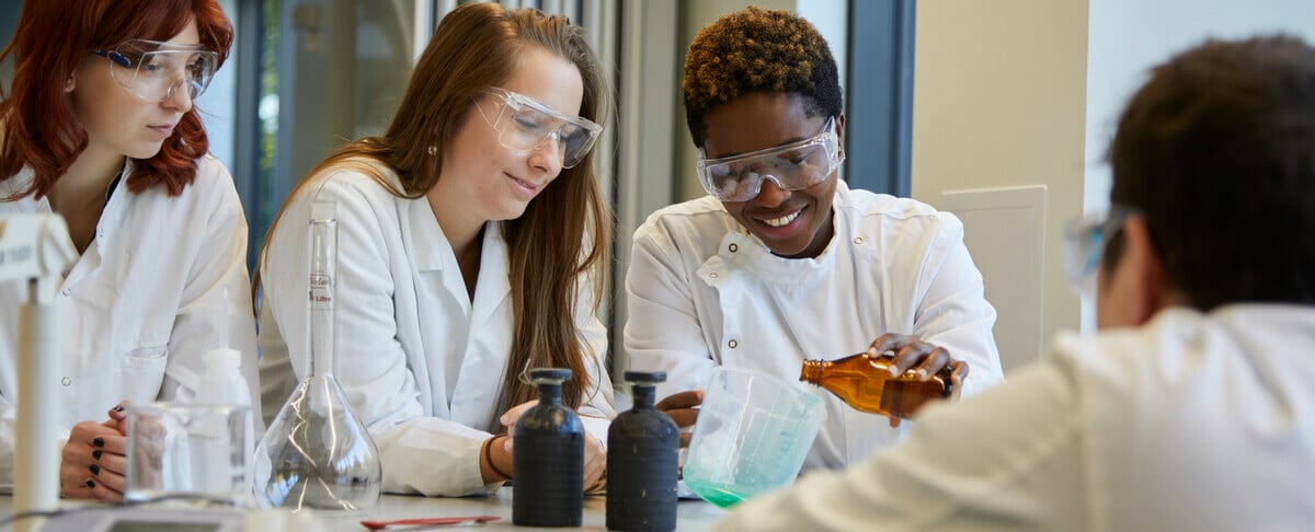 Three students in a laboratory doing a science practical