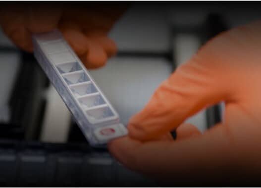 Orange gloved hands holding a small white device