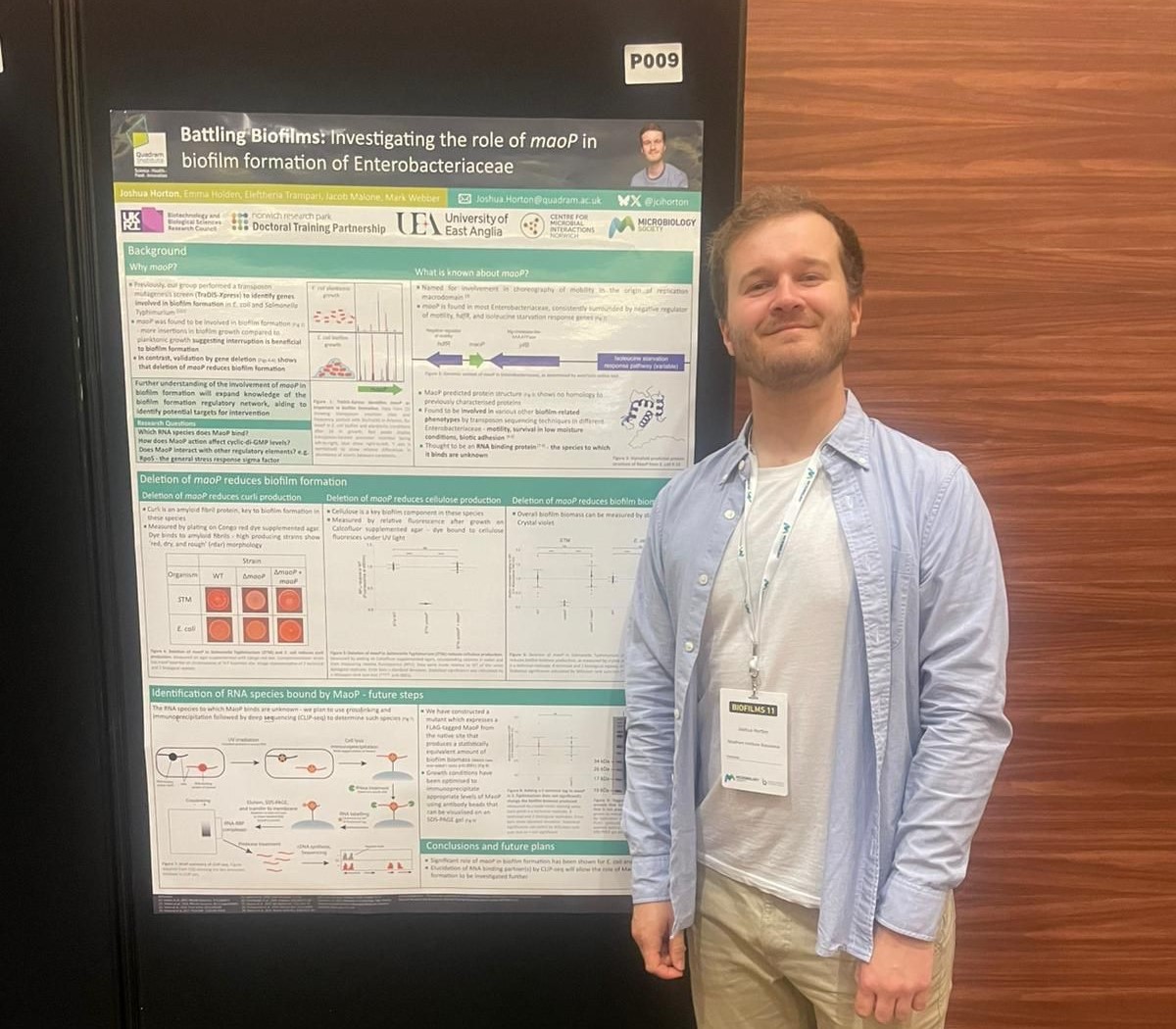 Joshua Horton standing next to his poster about biofilms research
