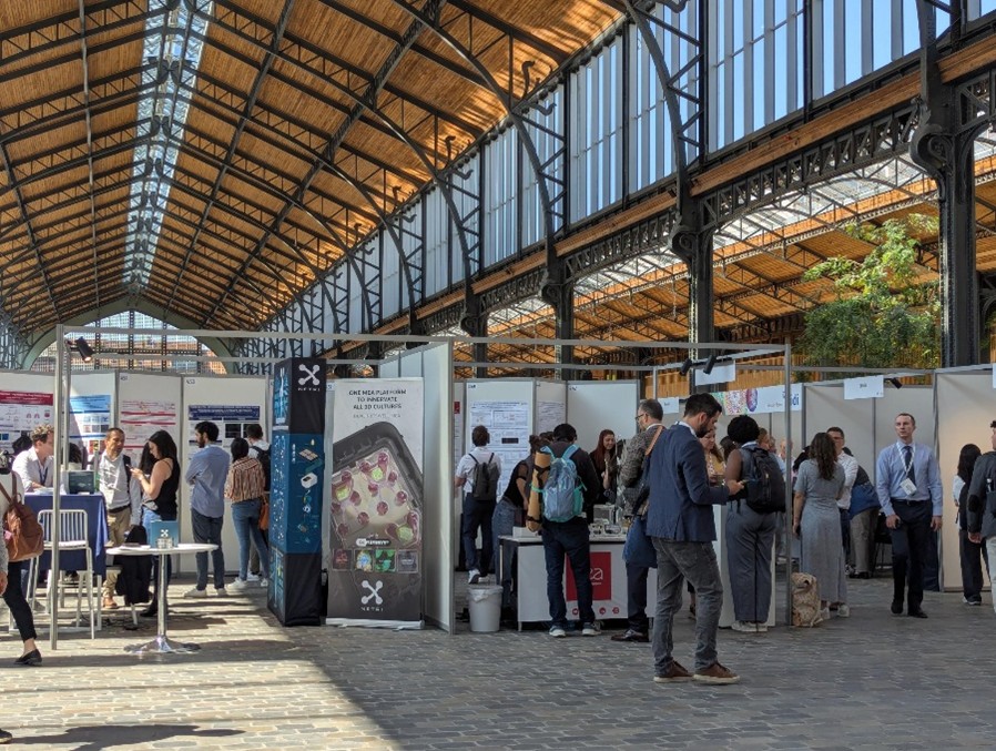 Conference attendees looking around posters and exhibits in a large hall