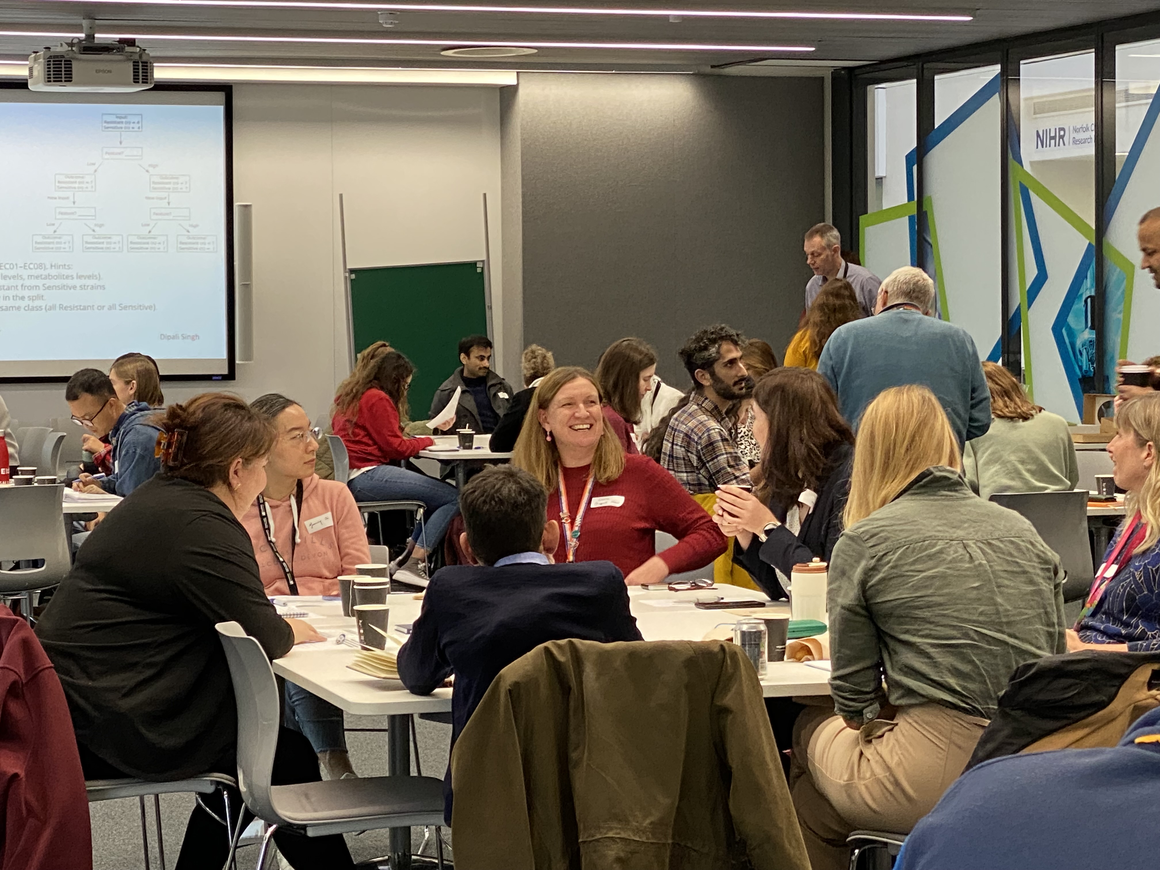 Attendees at the functional multi-omics symposium interacting around groups of small tables.
