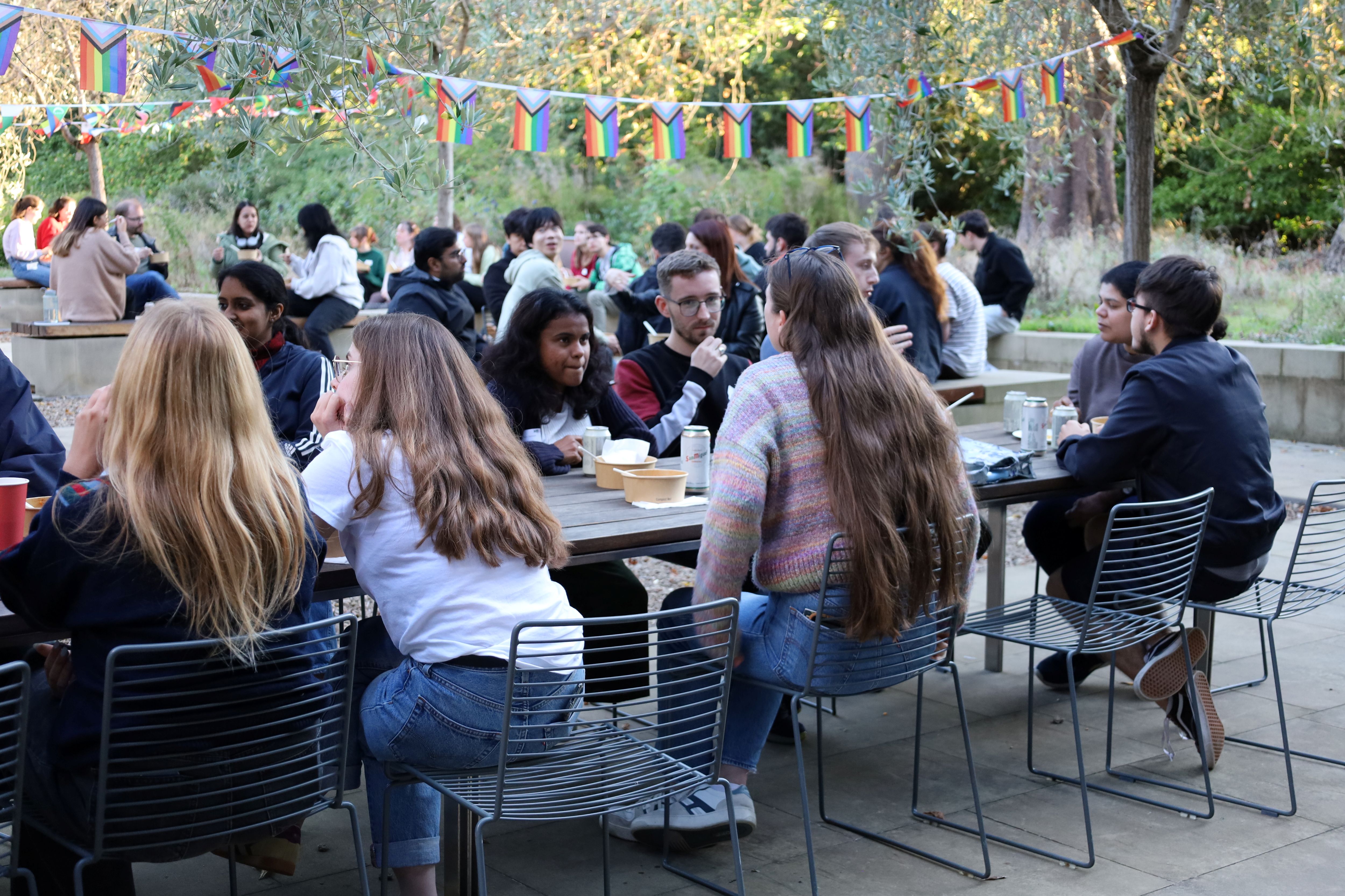 Groups of students sitting together and talking around tables outside