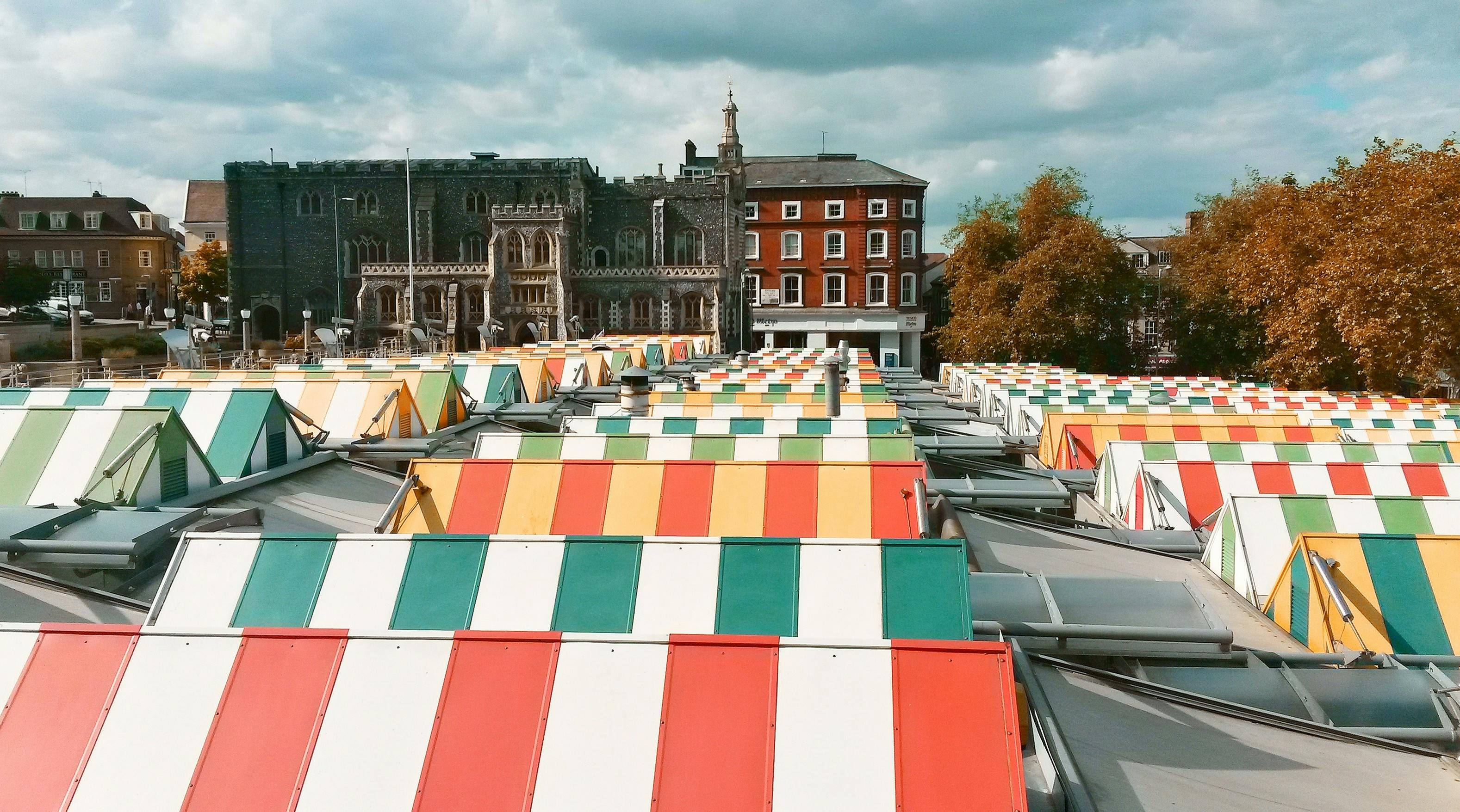 Colourful and stripey rooftops of Norwich Market stalls on a bright and cloudy day