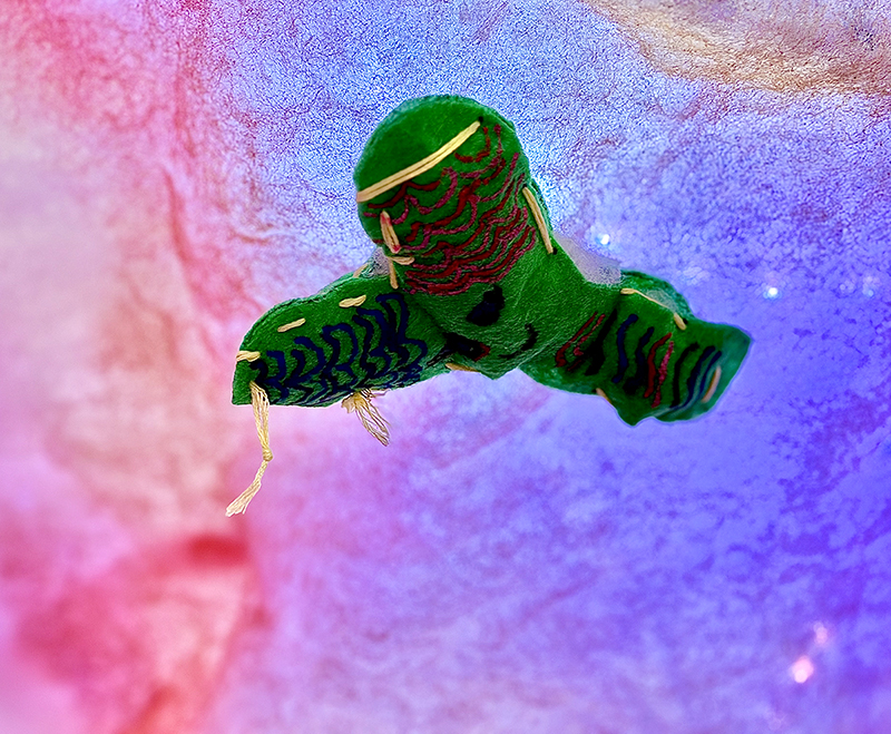 Greem Y-shaped bifidobacteria made of fabric hanging on purple and pink patterned background