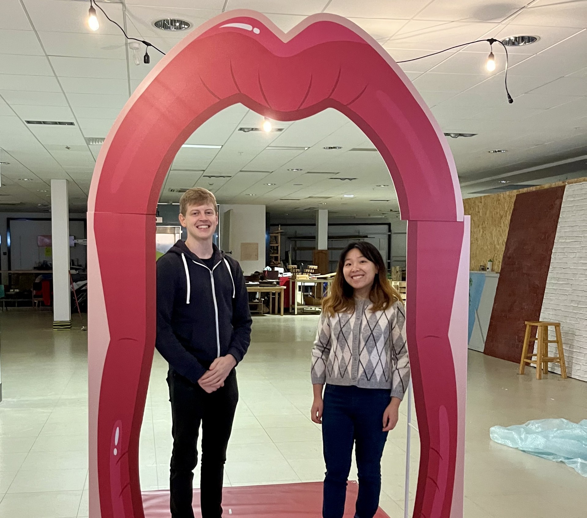 Sam Rowe and Ka Cheung standing on a cartoon tongue in the archway of a giant mouth.