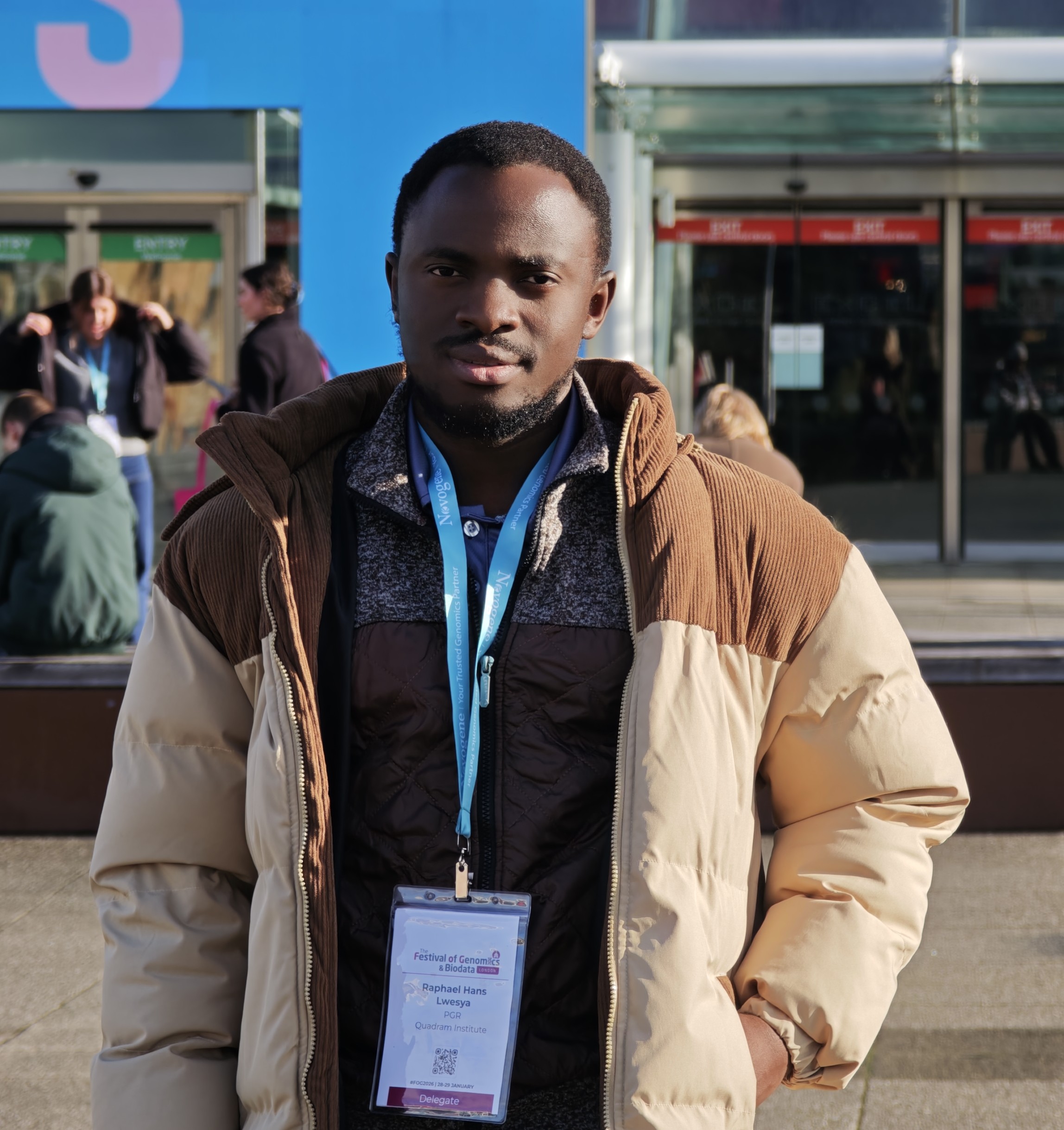 Raphael Hans Lwesya outside the Festival of Genomics venue wearing an event lanyard.