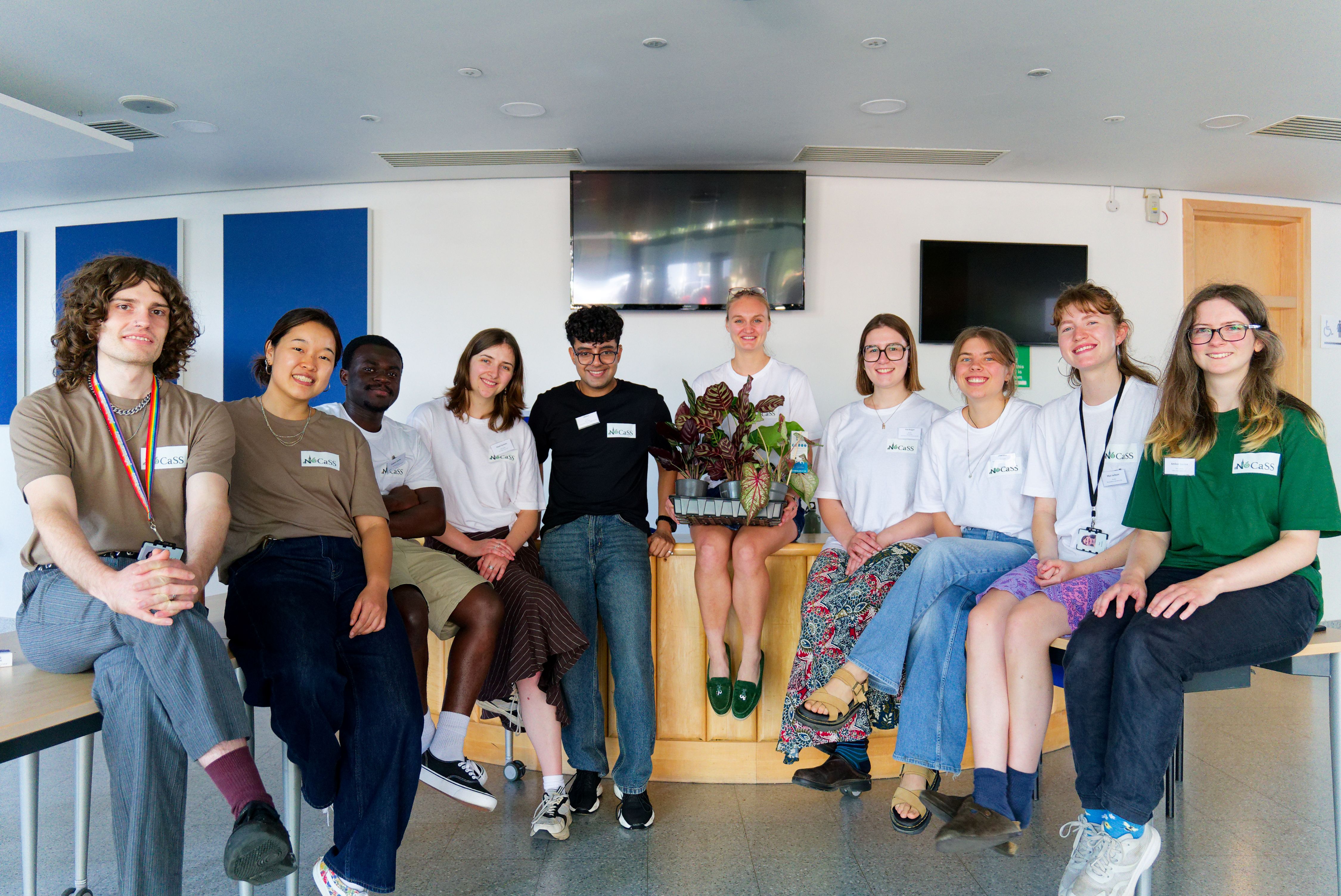 The conference organising committee sitting and standing together around the front desk of the venue
